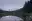 A tiny, 32-pixel-wide version of the lake photograph: a blue sky over a dark band of forest.